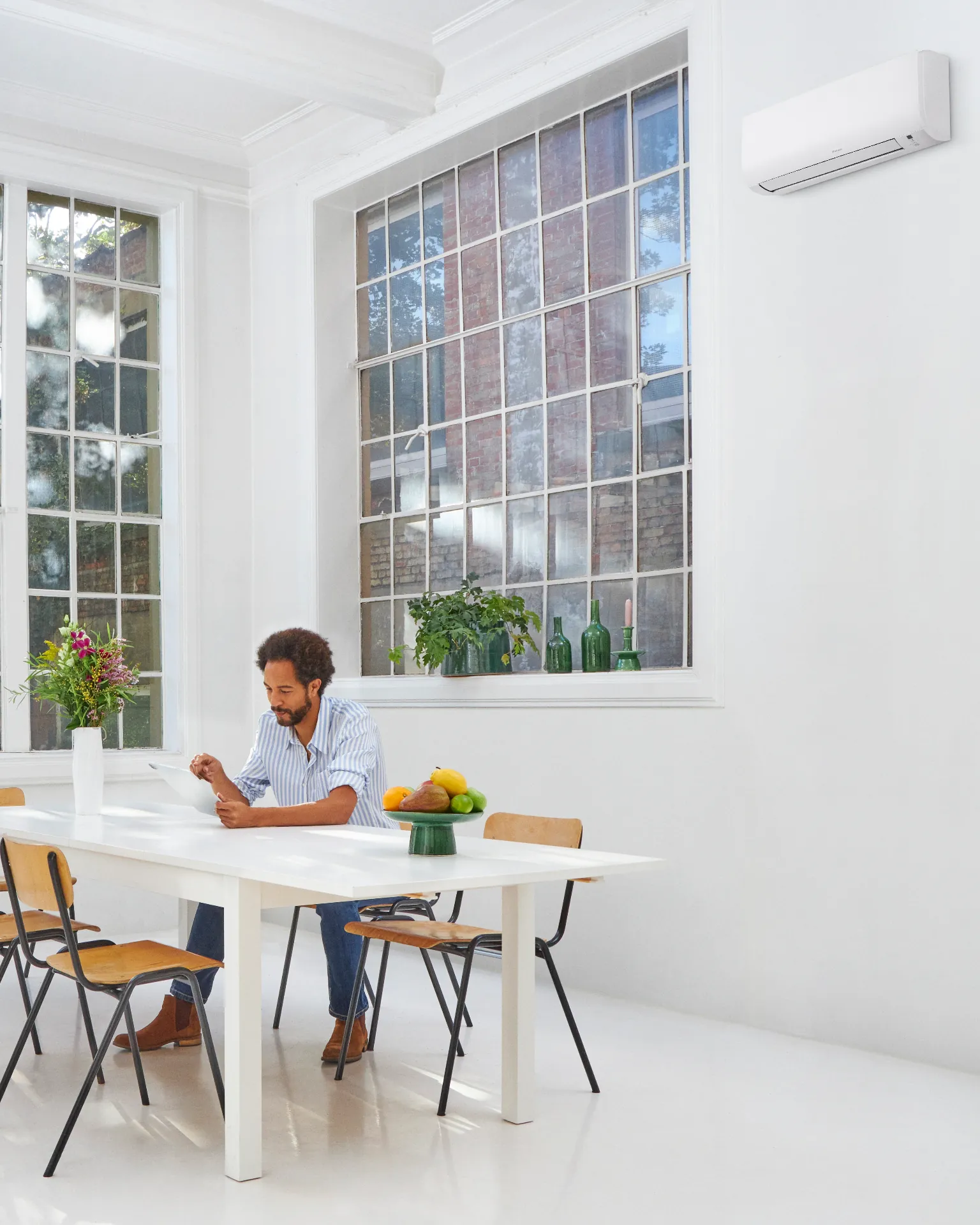 Daikin wall-mounted split air conditioning unit installed above a window in a bright loft-style commercial workspace