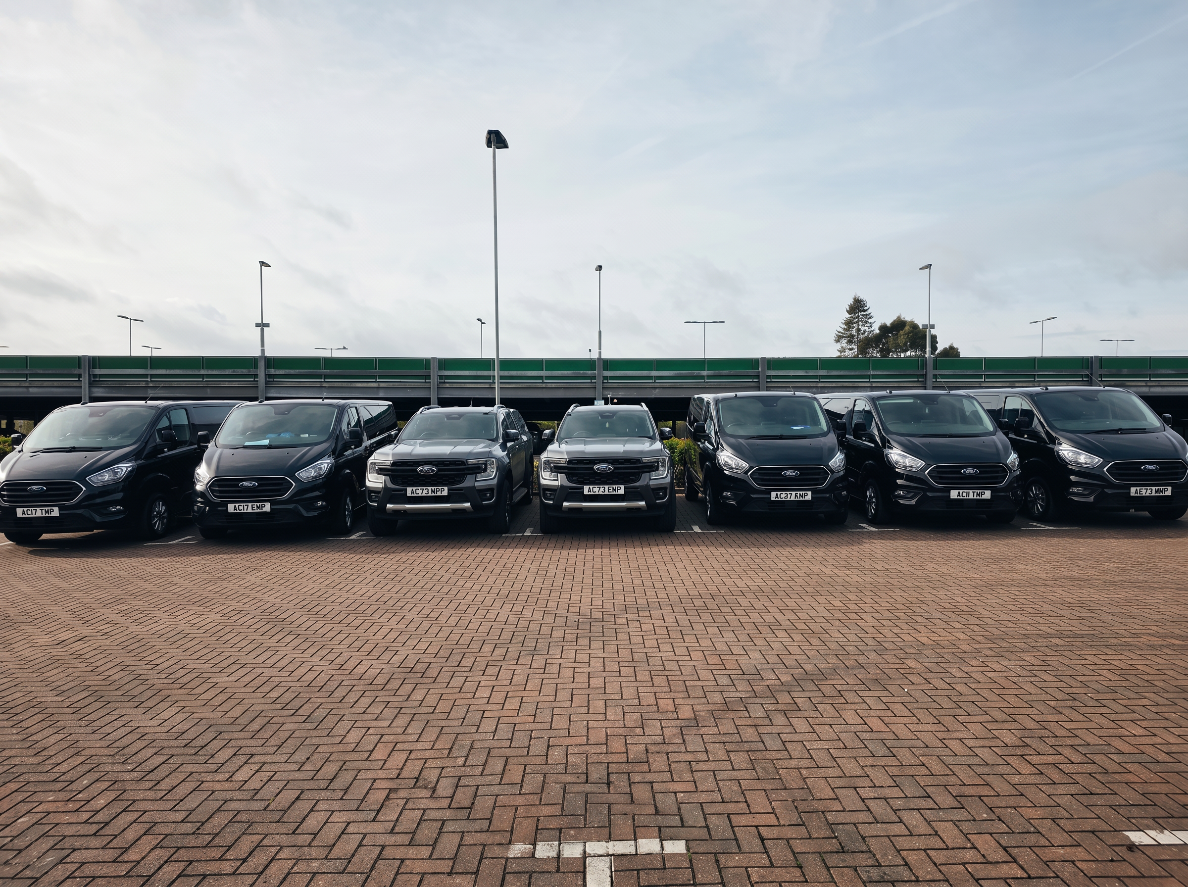 AccuTemp commercial AC engineer fleet — a line of black and grey Ford vans and pickups at the Coventry base