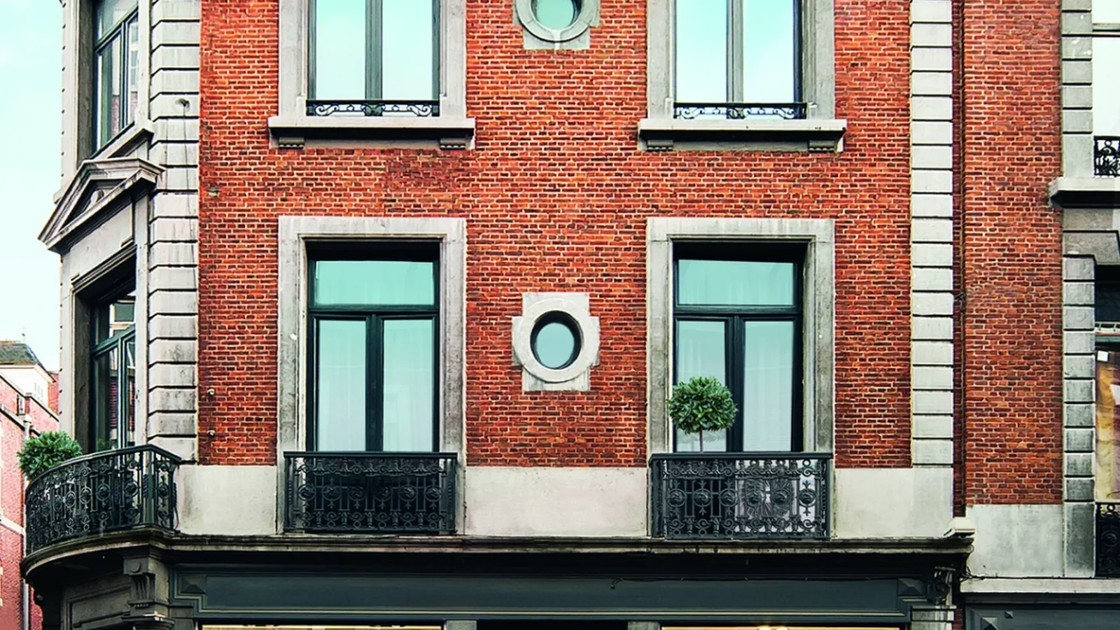 Heritage brick corner shopfront on a UK high street with an active ground-floor retail tenant — AccuTemp commercial air conditioning installed sympathetically inside a conservation-area building.